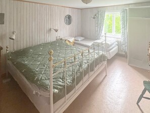 Une chambre avec un lit simple, une table de chevet, un miroir et une fenêtre avec des rideaux.