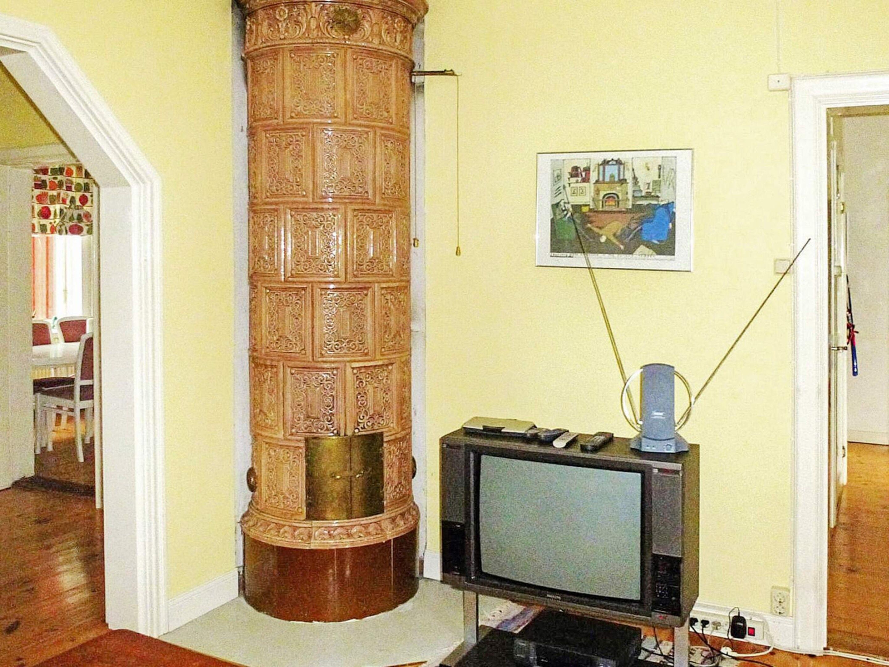 A room with a wooden pillar, a television, and a painting on the wall.