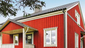 A red wooden house with a porch, a chimney, and a window. - 7 Person Holiday Home in Algaras (Älgarås)
