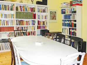 A room with a white table surrounded by chairs, a bookshelf filled with books, and a framed picture on the wall. - 7 Person Holiday Home in Algaras (Älgarås)