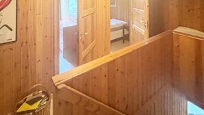 A wooden interior with a staircase leading to a bedroom.