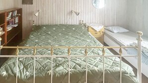 A room with a bed, a bedside table, a lamp, a mirror, and a bookshelf.
