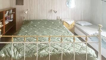 Una habitación con una cama, una mesita de noche, una lámpara, un espejo y una estantería.