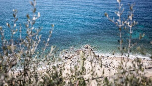 A coastal landscape with clear blue water, rocky shoreline, and sparse vegetation. - A corner of paradise waiting only for you! (JOPPOLO)