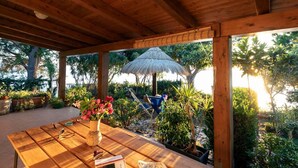 An outdoor wooden deck with a table, a thatched umbrella, and potted plants. - A corner of paradise waiting only for you! (JOPPOLO)
