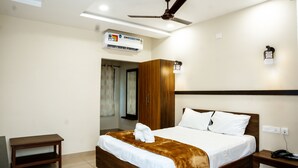 Hotelkamer met een bed, nachtkastje, plafondventilator, airconditioning en een telefoon.