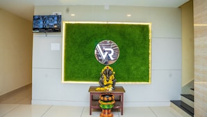 Een receptiezone met een VR-logo, een televisie en een standbeeld op een voetstuk.
