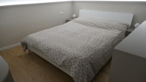 A bedroom with a bed, a nightstand, and a small bedside table. - Opera Suites - Aida (Palermo)