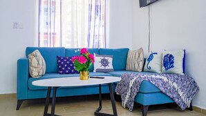 A living room with a blue sofa, a white coffee table, and a TV mounted on the wall. - Beautiful 2-bed Villa in Punta Cana Bavaro (Punta Cana)