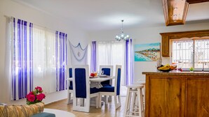 A dining area with a table and chairs, a bar counter, and a painting on the wall. - Beautiful 2-bed Villa in Punta Cana Bavaro (Punta Cana)