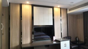 Una habitación de hotel moderna con una cama grande, un escritorio con computadora, una silla y una mesita.
