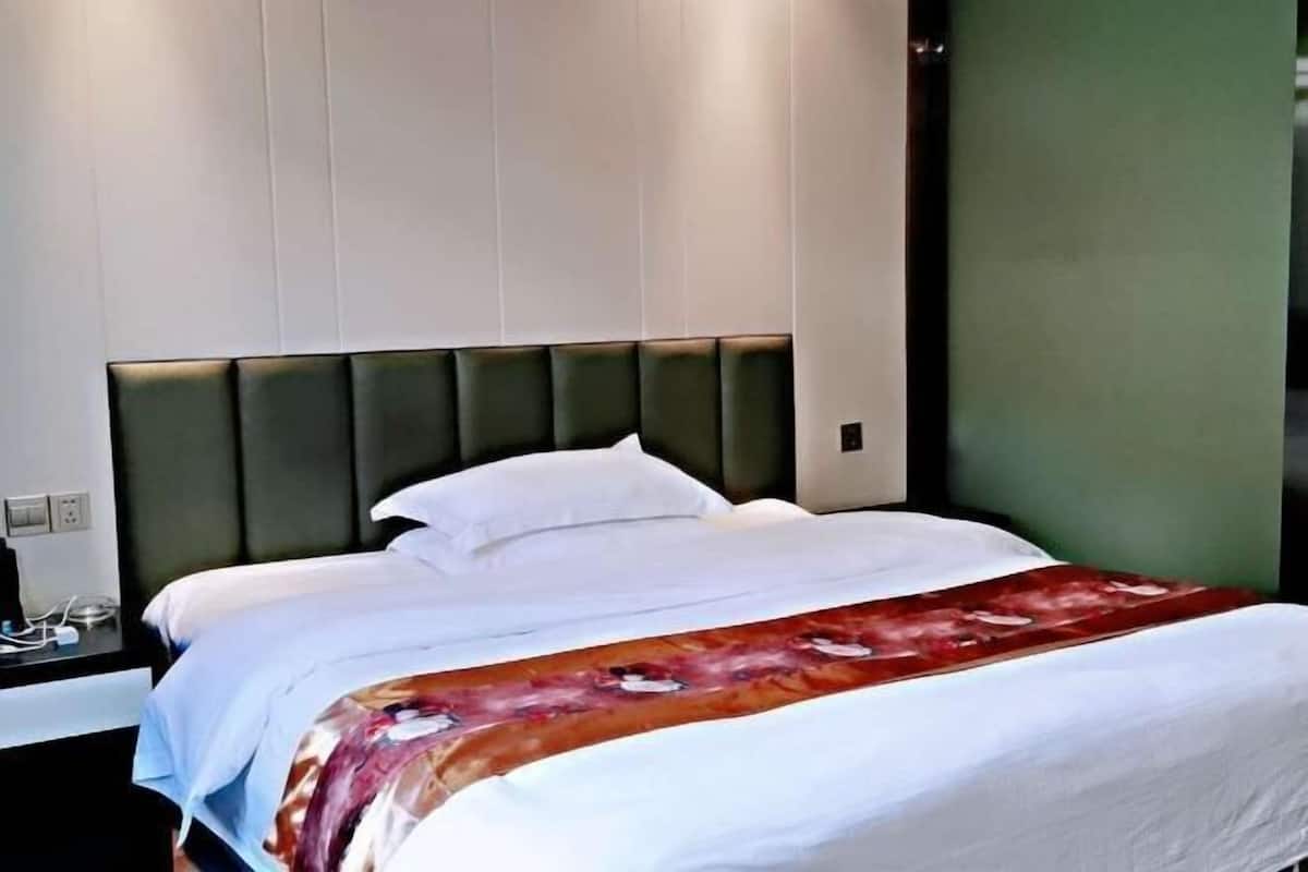 A hotel room with a bed, a nightstand, and a green wall.