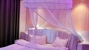 Una cama con dosel, mesitas de noche y una lámpara fijada a la pared.