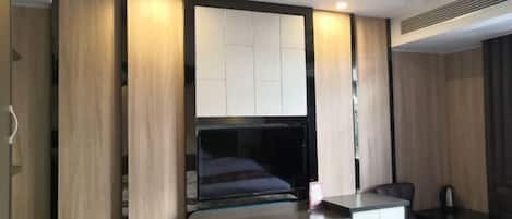 A modern hotel room with a bed, a desk, and a seating area.
