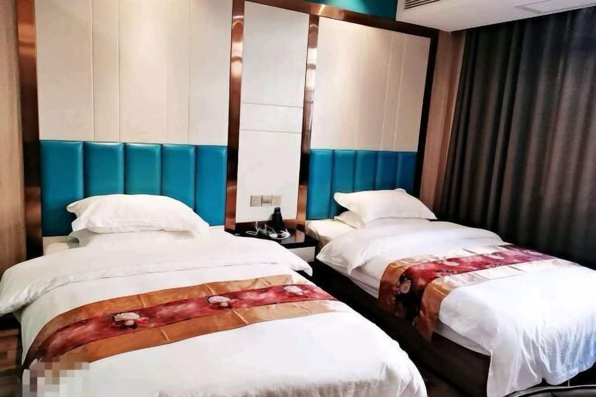 A hotel room with two single beds, a large mirror, and a dark curtain.