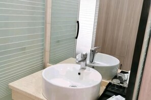 Un baño con dos lavamanos, un espejo y una ventana con persianas.