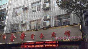 Fachada de hotel con múltiples unidades de aire acondicionado, un letrero rojo con caracteres chinos y un panel de señalización digital con texto rojo.