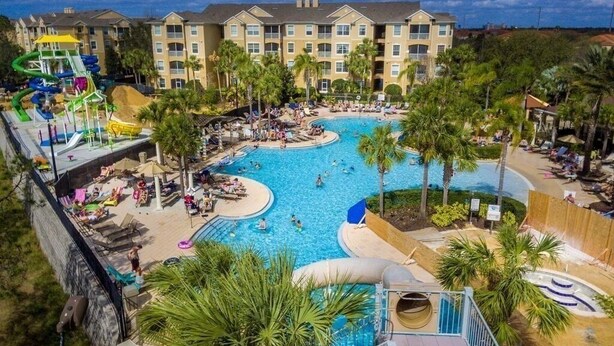 A resort with a large central pool, multiple water slides, and a building with balconies.