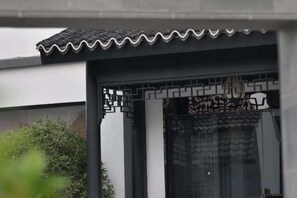 A traditional gate with intricate patterns, a tiled roof, and a modern building facade. - Shushan Lanting Boutique Hostel (Suzhou)
