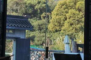A traditional building with a tiled roof and a gate, surrounded by lush greenery. - Shushan Lanting Boutique Hostel (Suzhou)