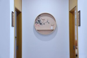 A hallway with a round wall-mounted shelf displaying a floral artwork. - Shushan Lanting Boutique Hostel (Suzhou)