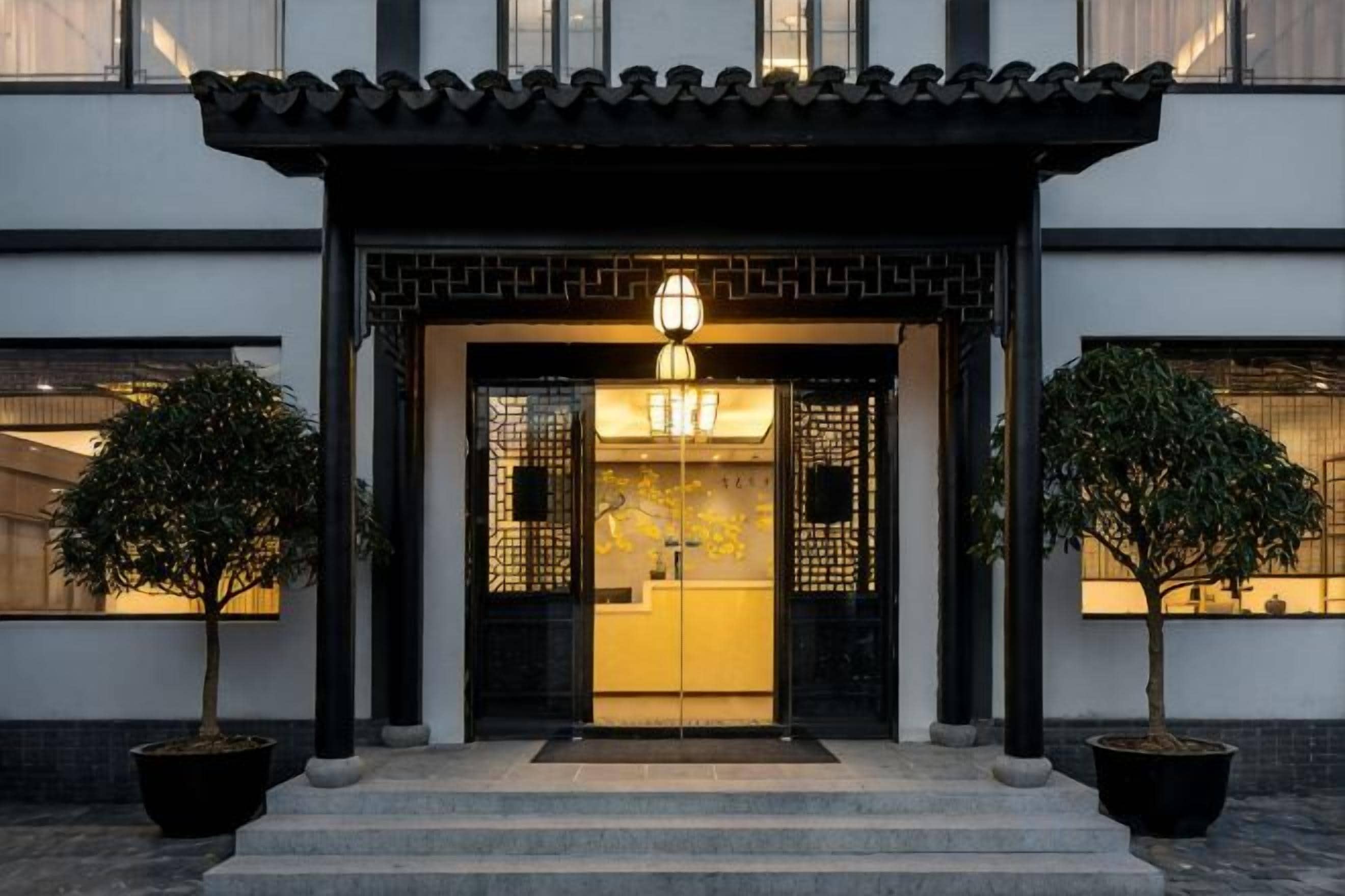 A traditional building entrance with a tiled roof, a black gate, and a light fixture above the door.