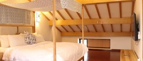 Una habitación con cama con dosel, vigas de madera y un televisor en la pared.