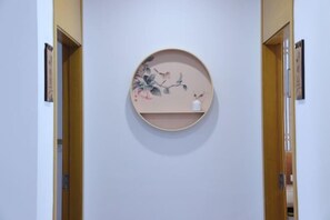 A hallway with a round wall-mounted shelf displaying a floral artwork. - Shushan Lanting Boutique Hostel (Suzhou)