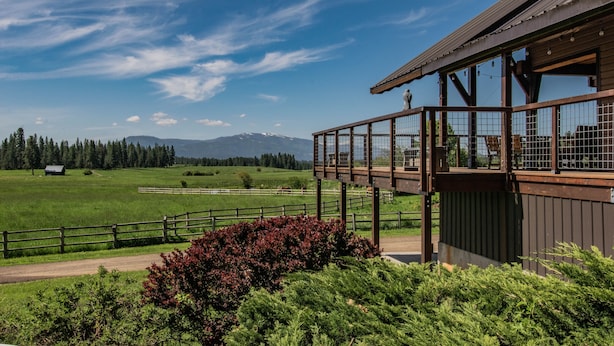A wooden building with a balcony overlooking a green field and mountains. - Exclusive Mountain Grandeur!
Back door to the Seven Devils Mountain range (Council)