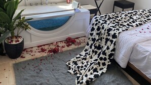 A room with a bathtub, a bed, a small table, and a view of the city. - Pyramids view apartment with hot tub jacuzzi (Giza)