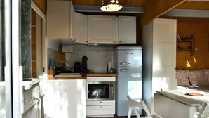 A compact kitchen with white cabinets, a built-in oven, a coffee maker, and a small refrigerator. - Chalet with private spa, garden, all within walking distance. (Saint-Rémy-de-Provence)