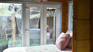 A bedroom with a bed, a pink pillow, and a wooden ceiling. - Chalet with private spa, garden, all within walking distance. (Saint-Rémy-de-Provence)