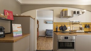 Een moderne keuken met roestvrijstalen apparatuur, een houten aanrechtblad en een zichtbare eethoek met een bank.