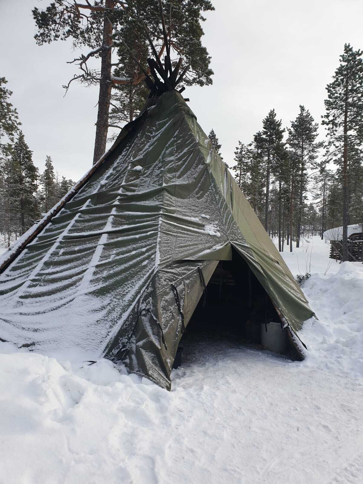 Una tenda teepee imbiancata dalla neve in una foresta.