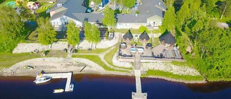 An aerial view of a lakeside property with a dock, boats, and houses.