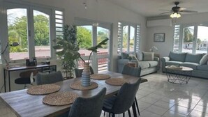 A spacious living area with a dining table, chairs, and a sofa. - The Enchanted Pearl come immerse yourself in relaxation and crystal clear waters (Vega Baja)
