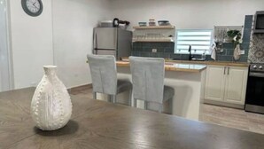Une cuisine moderne avec une table à manger en bois, des chaises grises et un vase blanc.