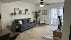 Un salon avec un canapé, une table basse, un tél éviseur et un ventilateur de plafond.