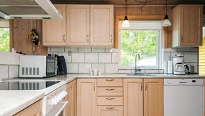 Een moderne keuken met houten kasten, een ingebouwde oven, een magnetron, een koffiezetapparaat en een vaatwasser.