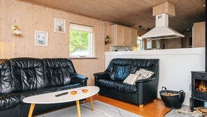 Een gezellige woonkamer met twee zwarte leren banken, een witte salontafel en een open haard.