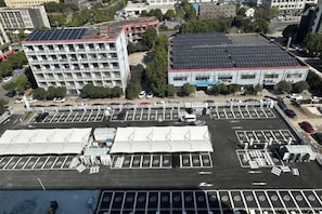 Un estacionamiento con varias filas de espacios, un edificio con techo solar y una gran estructura tipo carpa.
