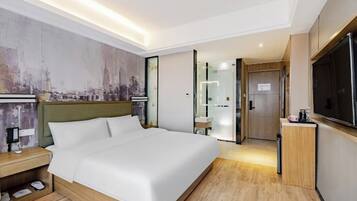 A modern hotel room with a large bed, a television, a nightstand, and a cityscape mural on the wall.