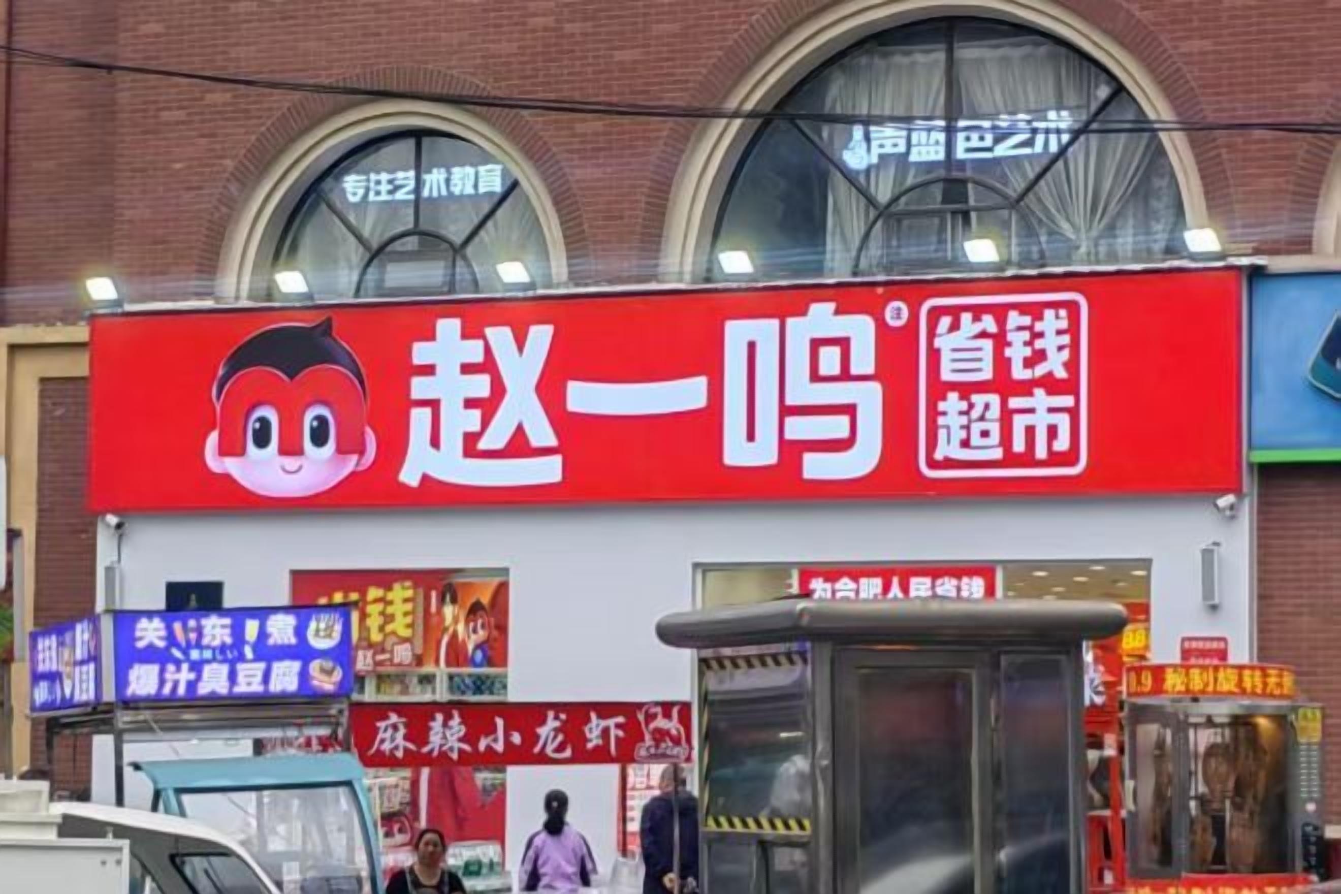 Un escaparate rojo con logotipo de un personaje de caricatura, un cartel azul y un pequeño quiosco.
