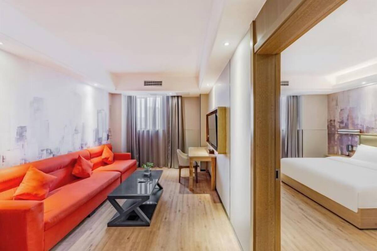 A hotel room with a bed, a sofa, a desk, and a chair.