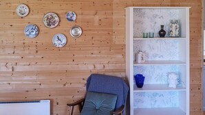 Ett rum med en väggpanel av trä, en vit bokhylla och en blå stol med en kudde.