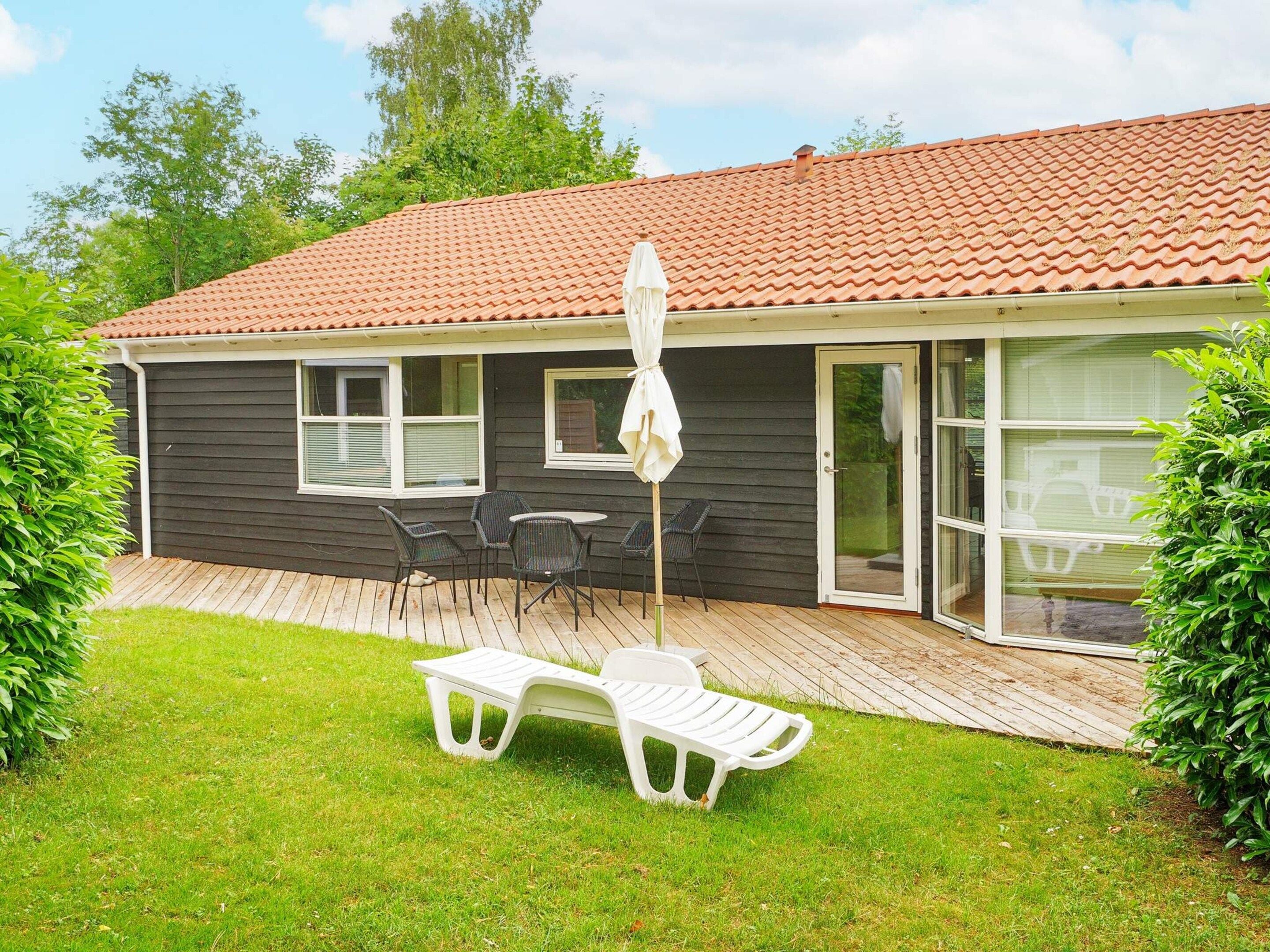 A house with a patio area featuring a table and chairs, a white umbrella, and a sliding glass door.