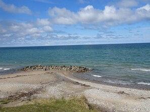 Une plage avec une digue rocheuse, une mer calme et un ciel dégagé.