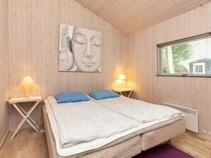 Une pièce comprenant un lit, deux tables de chevet, une œuvre d’art accrochée au mur, une fenêtre et un radiateur.