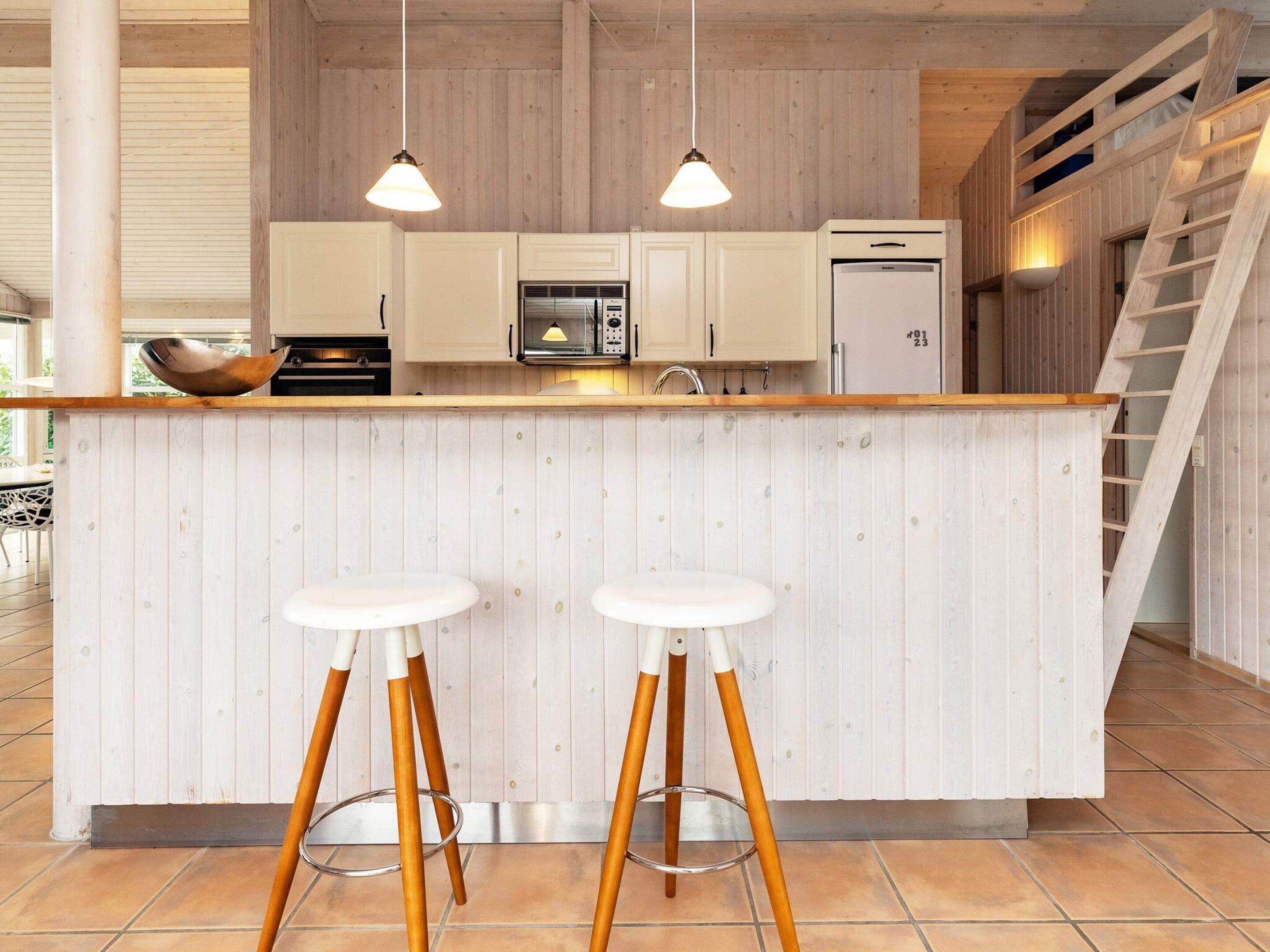 Eine Küche mit Holzausstattung, einer Mikrowelle, einem Kühlschrank und zwei Barhocker.