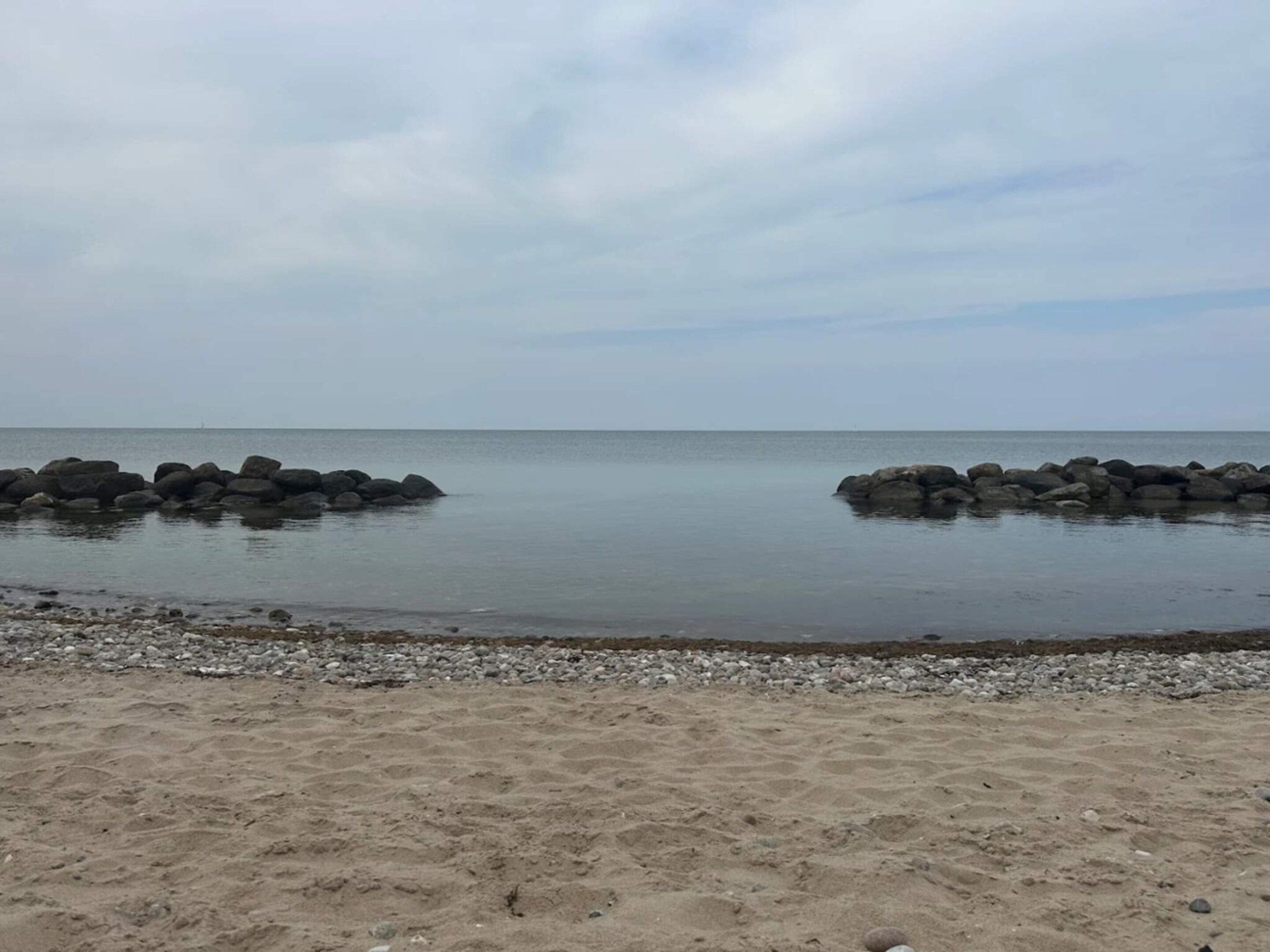 A beach with a rocky breakwater and a sandy shore.